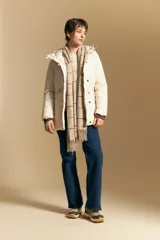Campera acolchada de nylon en color crema, con capucha ajustable, cierre frontal con botones y cordón de ajuste en la cintura.