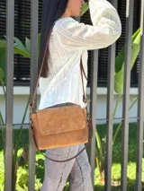 Cartera bandolera de cuero gamuzado color camel, con solapa frontal y cierre principal. Incluye dos correas desmontables, una corta y una larga regulable, y cuenta con bolsillo interior.