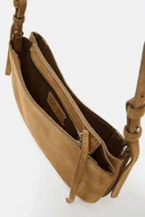 Bandolera de serraje color marrón con doble compartimento, uno con cierre de cremallera y otro con cierre magnético. Presenta pespuntes en contraste y asa larga ajustable.