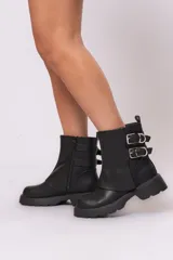Botas biker cortas de cuero sintético negro, con suela track, cierre lateral con cremallera y doble hebilla decorativa.