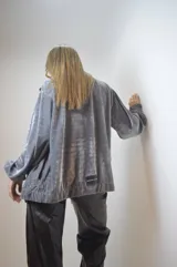 Campera gris de terciopelo con cierre frontal, cuello alto y mangas largas con puños elásticos.