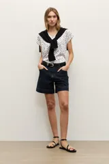 Short de jean azul oscuro, de tiro medio con bolsillos delanteros y traseros, costuras pespuntadas en contraste y dobladillo en las piernas.