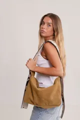 Bolso tipo hobo de gamuza color naranja quemado, con correa ancha de tela color bordó.