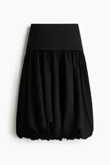 Pollera midi de corte globo en color negro, con diseño abullonado y pretina ancha lisa.