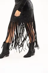 Pollera midi de cuerina negra con diseño ajustado en la parte superior y terminación en flecos largos que aportan movimiento.