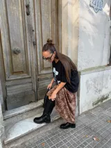 Bota de caña alta estilo biker, confeccionada en cuero sintético negro. Presenta una suela track con plataforma, puntera redondeada y un detalle de arnés con hebilla metálica y tachas en la zona del tobillo.