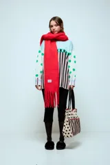 Sweater de punto con diseño estampado que combina lunares verdes, rombos y rayas verticales en tonos claros, negros y rojos. Presenta cuello redondo y mangas largas.