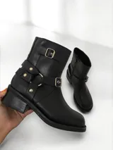 Bota corta de cuero negro con hebillas metálicas y cierre interno.