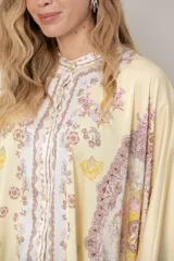 Camisa de seda modelo pañuelo, de color amarillo con estampado estilo mandala y flores, cuello redondo y cierre frontal con botones.