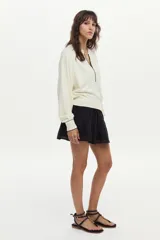 Sweater de tejido de punto color blanco marfil, con calce relajado, mangas largas levemente abullonadas, escote en V con botones y detalles de ribetes en color negro.