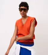 Chaleco de tricot naranja con escote en V profundo, hombreras internas y terminaciones acanaladas en cuello, sisas y bajo.