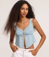 Top cropped de jeans celeste con escote corazón, breteles anchos y abertura frontal central abotonada. Los bordes del escote y la abertura están decorados con un ribete de encaje blanco tipo picot.