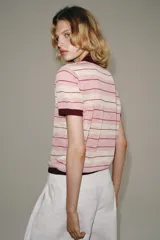Polo de punto de manga corta con diseño a rayas horizontales en tonos celestes, blancos y finas líneas marrones. Cuenta con cuello clásico y cierre frontal parcial con botones.