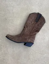 Botas de cuero color marrón y blanco con bordados negros, de estilo cowboy con taco bajo.