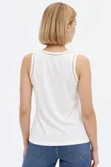 Musculosa blanca de algodón, de corte ajustado, con cuello redondo y detalles de broderie en los bordes.