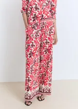 Pantalón largo de corte recto y tejido fluido, con estampado paisley en tonos rojo, bordó y crudo. Cuenta con cintura elástica con cordón ajustable y bolsillos laterales.