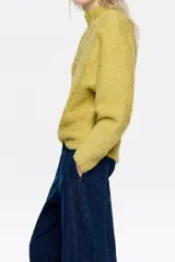 Jersey de textura suave y peluda, con cuello subido y manga larga, diseñado con un corte cómodo y envolvente.