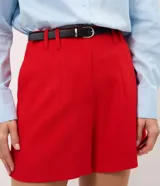 Short sastrero rojo de talle alto, con pinzas delanteras, cierre oculto y bolsillos traseros. Incluye un cinturón delgado de poliuretano.