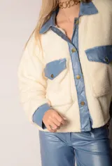 Chaqueta color crema de corderito con detalles en jean azul en cuello, solapa, bolsillos y puños.