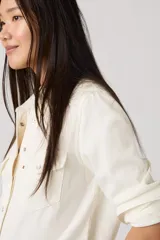 Camisa Levi's estilo western de corte estándar, color crema, con mangas largas, cuello clásico y cierre frontal con botones a presión. Presenta dos bolsillos frontales con solapa y etiqueta roja característica de la marca.