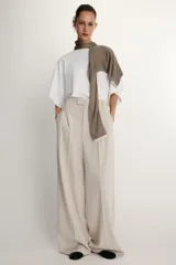 Camiseta blanca de manga corta con corte oversize y cuello redondo. El diseño presenta mangas amplias tipo capa que caen desde el hombro.