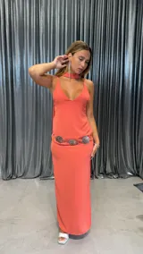 Vestido largo color coral con escote en V y tirantes finos. La tela presenta una textura arrugada o plisada.
