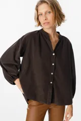 Camisa de algodón con textura de pana, color azul marino, de corte holgado, cuello mao con escote en V y mangas largas abullonadas con puños elásticos.