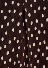 Vestido midi de corte recto con estampado de lunares, cuello en pico y mangas cortas. Presenta cierre de cremallera lateral y abertura en el bajo.