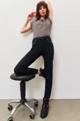 Pantalón de jean negro, corte slim, con tachas metálicas plateadas decorando la abertura de los bolsillos delanteros.