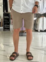 Bermuda de lino color beige, de corte recto con bolsillos laterales y cintura elastizada con cordón ajustable.