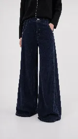 Pantalón de pana de algodón con tiro medio y corte de pierna ancha. Presenta dos bolsillos delanteros, dos bolsillos traseros con pespuntes y cierre frontal con botón y cremallera.