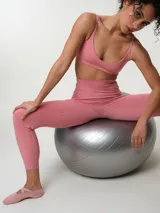 Top deportivo de breteles finos regulables, color rosado, con diseño liso y escote redondo.