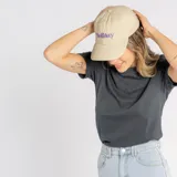 Gorro tipo baseball color beige, con visera curva y bordado frontal con la palabra Holiday en color violeta.