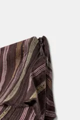 Falda pantalón corta con diseño de volantes superpuestos, confeccionada en tejido estampado a rayas con hilos metalizados. Cuenta con forro interior y cierre lateral con cremallera oculta.