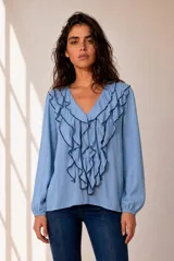 Blusa celeste de manga larga con escote en V y volados en cascada ribeteados en color oscuro. Cuenta con puños elásticos.