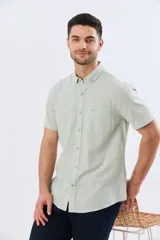 Camisa de manga corta confeccionada en mezcla de lino y algodón, color beige, con cuello camisero abotonado, bolsillo frontal en el pecho y cierre de botones.