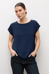 Blusa blanca con textura plumeti, de manga corta y cuello redondo.