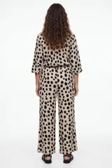 Pantalon tipo palazzo color negro con estampado paisley en tonos beige y blanco, corte holgado y tiro medio.