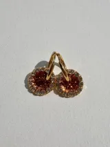 Aros de acero quirúrgico con dije circular de resina rosa y borde de strass dorados.