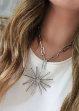 Collar plateado con cadena de eslabones rectangulares y dije en forma de sol con rayos.