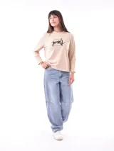 Remera de manga larga color beige, con cuello redondo y estampado frontal que dice "Magic is something you make" en color lila.