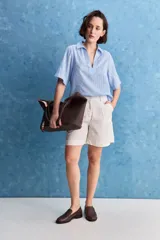 Blusa celeste de manga corta con cuello camisero y escote en V, confeccionada en tejido liviano con textura sutil y estampado de lunares.