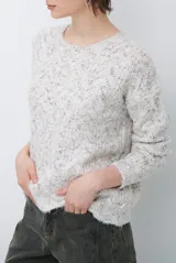 Buzo de tejido de punto con cuello redondo, mangas largas y textura jaspeada en tonos neutros.