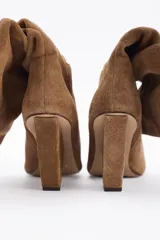 Botines dorados de cuero vacuno con punta fina y tacón aguja.