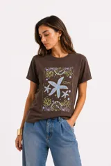 Remera de manga corta color beige, con cuello redondo y diseño al cuerpo. Presenta un estampado frontal multicolor de estilo veraniego con temática marina y detalles con glitter.