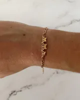 Pulsera de acero quirúrgico color dorado, con cadena de eslabones y dijes centrales de tres mariposas caladas con diseño ornamental.