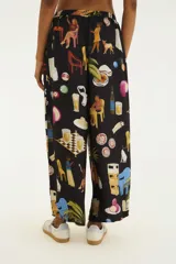 Pantalón negro de calce amplio y recto, confeccionado en viscosa liviana. Presenta una estampa colorida con ilustraciones estilo collage urbano, cintura elástica con cordón de ajuste y diseño fluido.