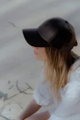Gorra de béisbol negra de cuero sintético con hebilla metálica ajustable en la parte posterior.