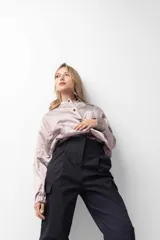 Pantalón gris de tiro alto con pinzas, bolsillos cargo laterales y ruedo ajustable con botones.