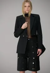Blazer negro de corte estructurado con diseño de abotonado desmontable en la cintura, que permite separar la parte inferior de la prenda. Presenta solapas clásicas, hombreras marcadas y cierre frontal con botones metálicos.